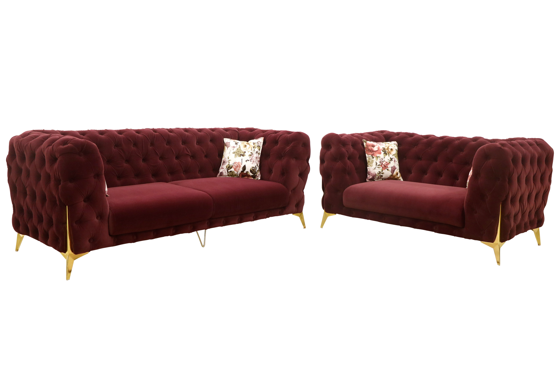 A pair of luxurious, tufted burgundy velvet sofas with elegant gold legs. Each sofa is adorned with floral-patterned cushions, creating a rich and inviting atmosphere.